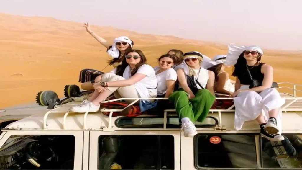 A group of travelers sitting on top of a 4x4 roof rack in the Erg Chebbi dunes during a Morocco Atlas Mountains Desert Merzouga 6 day Itinerary.