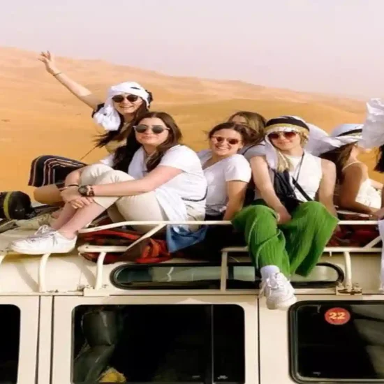 A group of travelers sitting on top of a 4x4 roof rack in the Erg Chebbi dunes during a Morocco Atlas Mountains Desert Merzouga 6 day Itinerary.