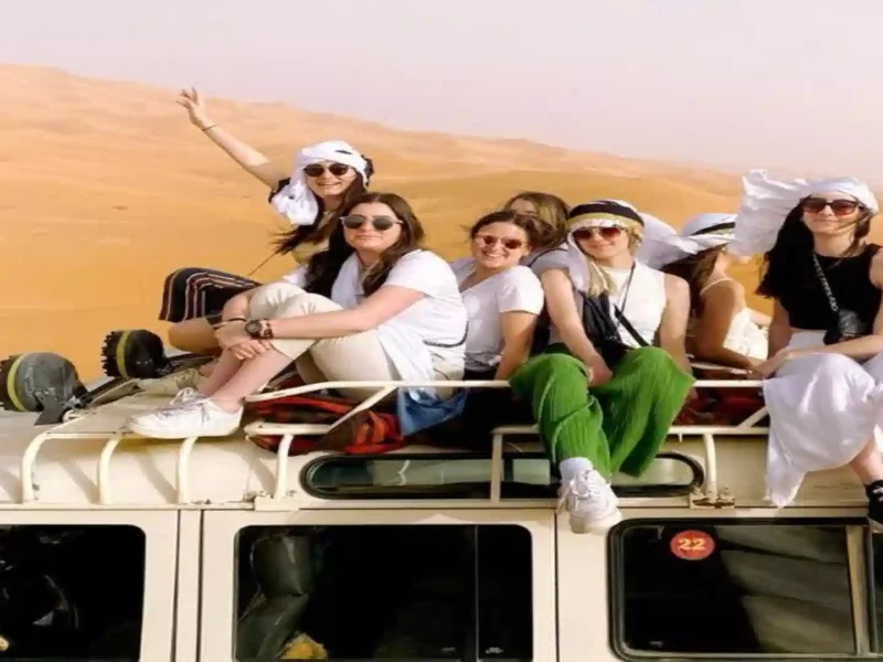 A group of travelers sitting on top of a 4x4 roof rack in the Erg Chebbi dunes during a Morocco Atlas Mountains Desert Merzouga 6 day Itinerary.