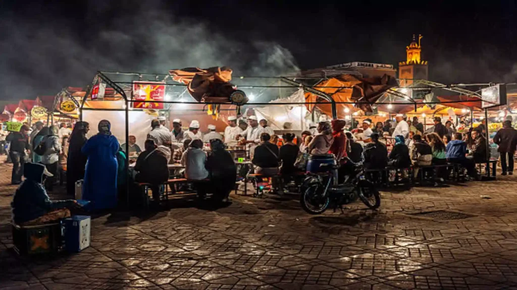 Djemaa el Fna Marrakech food stalls at night Marrakech — numbered stalls with charcoal grills and communal dining under open sky, Over Morocco Tours 2026