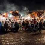 Djemaa el Fna Marrakech food stalls at night Marrakech — numbered stalls with charcoal grills and communal dining under open sky, Over Morocco Tours 2026