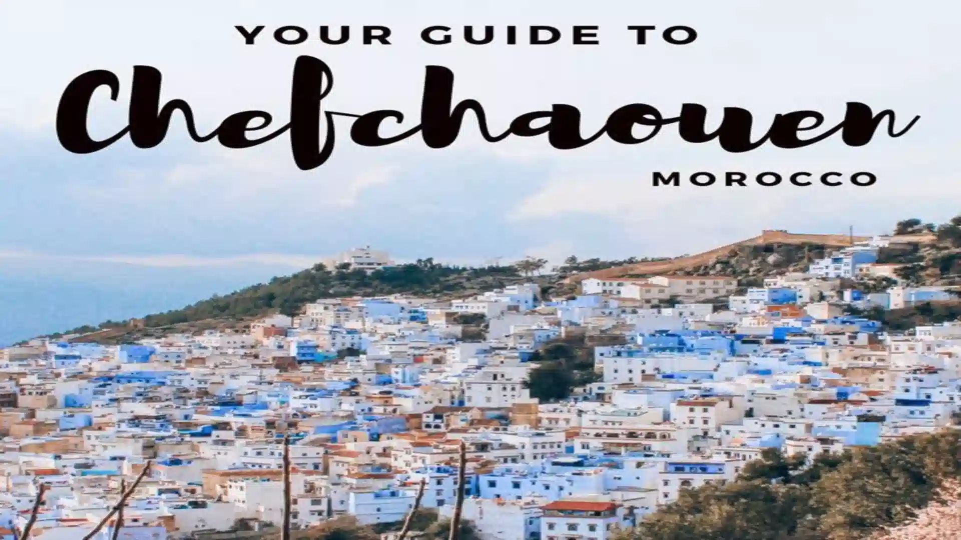 View of Chefchaouen's blue-and-white medina cascading down the hillside framed by green tree leaves in the foreground. why is Chefchaouen blue?