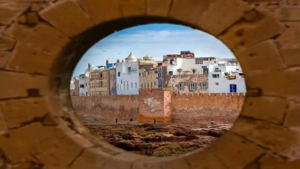 A framed circular view showing the whitewashed medina buildings and ancient stone sea walls of Essaouira. things to do in Essaouira.