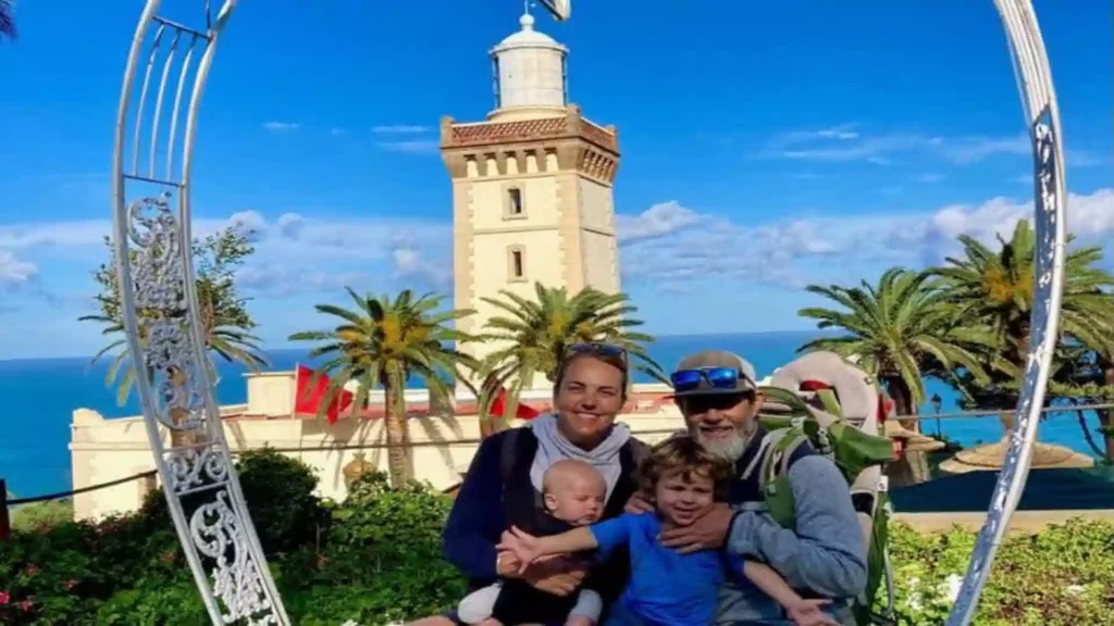 A family posing for a picture inside a decorative metal frame with Cap Spartel Lighthouse and the ocean in the background. with things to do in Tangier Morocco