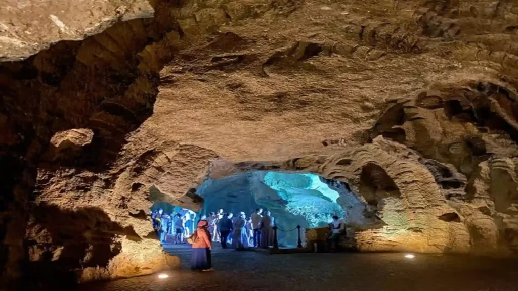 Visitors inside the cavernous Caves of Hercules looking toward the illuminated rock opening framed by natural stone walls.things to do in Tangier