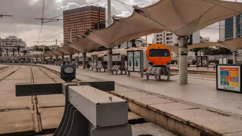 An orange and white modern tram at a shaded outdoor platform in an urban Moroccan city like Casablanca.