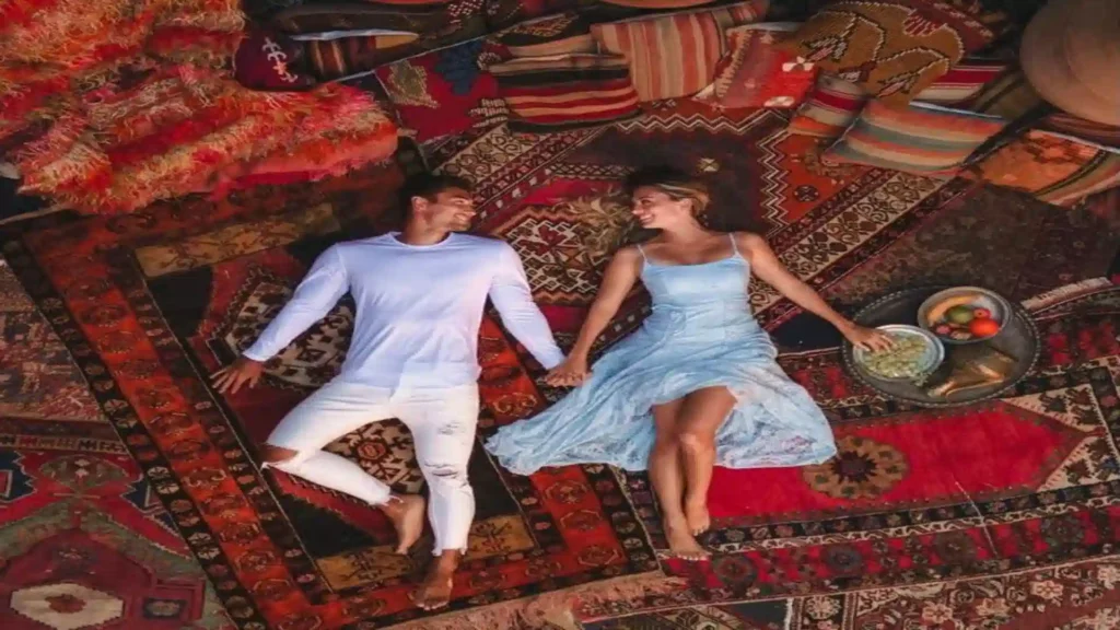 An overhead shot of a couple holding hands while relaxing on intricate Berber carpets during a Morocco luxury travel retreat.