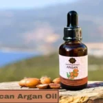 Moroccan argan oil glass bottle with dropper resting on a tree trunk against a scenic background