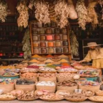 Traveler browsing woven baskets of spices, dried herbs, and pigments in an outdoor stall from the 7 best souks in Marrakech.